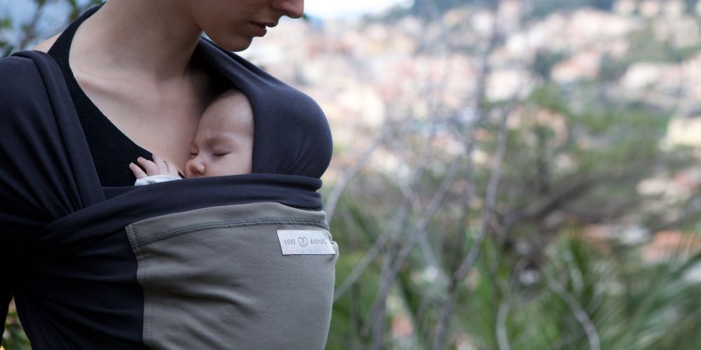 maman qui porte son bébé avec une écharpe de portage physiologique de couleur noir et poche anthracite de la marque Love Radius