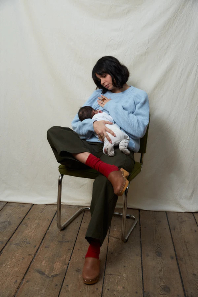 Femme portant un pull d’allaitement bleu océan en maille douce, confortablement assise avec son bébé | MUMMY NANTES