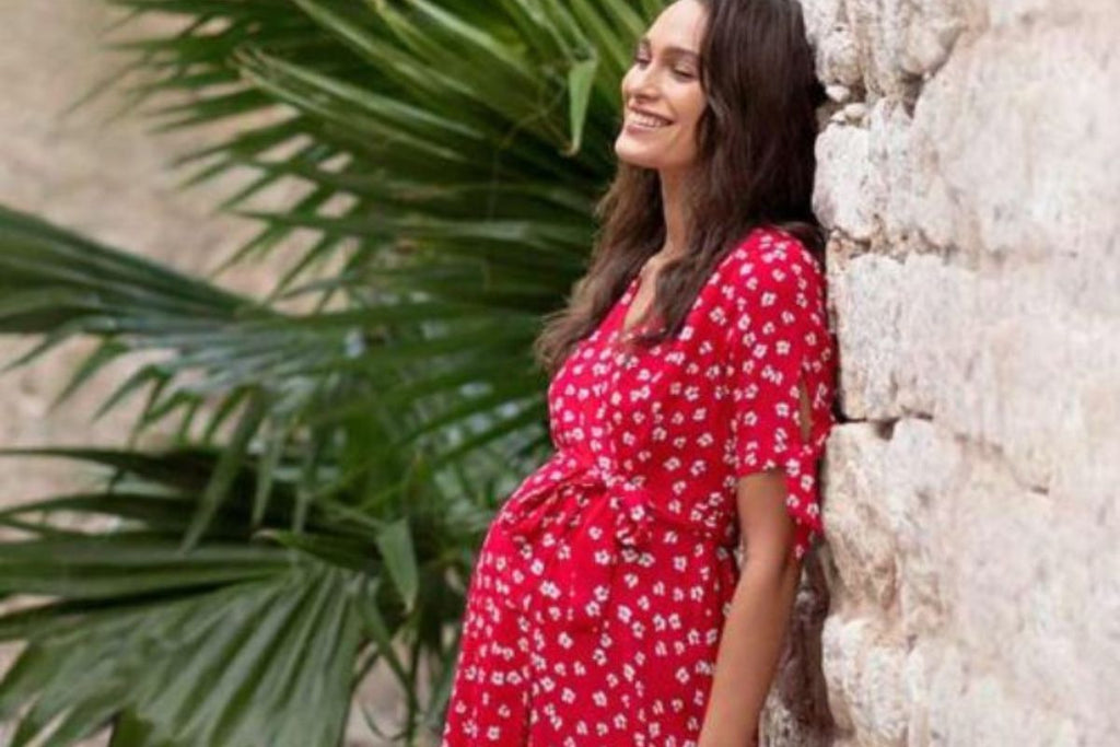 Femme enceinte en robe de grossesse rouge et imprimé blanc
